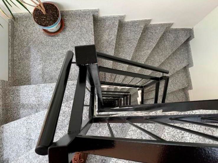 Vista desde arriba de escaleras y barandilla de portal