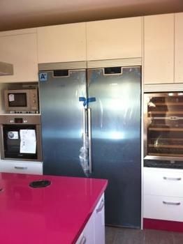 Cocina de encimeras magenta y nevera metálica de dos puertas